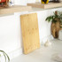 Large rectangular bamboo chopping board standing against kitchen wall