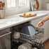 Non-stick frying pan with gold handle placed in dishwasher, kitchen setting