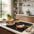Set of three non-stick frying pans with gold handles on induction hob, eggs, stew, vegetables