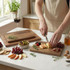 Set of wooden chopping boards with fruit, crackers and herbs arranged on a kitchen countertop