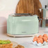 Green two-slice toaster on kitchen counter, shown with eggs and avocado toast