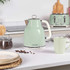 Green electric kettle on kitchen counter, next to matching mug and coffee beans.