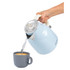 Light blue electric kettle pouring hot water into a grey mug, studio product image
