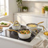 White and gold saucepan set with glass lids on induction hob, cooking vegetables and pasta