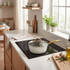 Cream saucepan with gold handle and lid on induction hob in modern kitchen