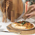 Acacia wood salt or pepper mill in use beside a plate of chicken, salad, and couscous