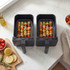 Two black air fryer baskets with chicken and vegetable skewers on a kitchen counter