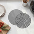 Set of two round grey air fryer liners, one solid and one with holes, on kitchen worktop