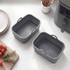 Set of two grey silicone air fryer liners with handles on marble worktop