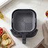 Grey silicone air fryer liner in square shape, placed inside black air fryer basket