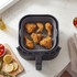 Cooked crispy chicken pieces in a grey air fryer basket, shown from above