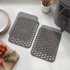Pair of grey perforated silicone air fryer liners shown on a kitchen counter