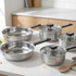 Set of five stainless steel saucepans and frying pans with lids on kitchen worktop