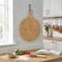 Round bamboo pizza board with slicing guides hanging in a modern kitchen