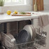 Open dishwasher with clean plates, cutlery, and glassware in modern kitchen setting