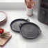 Two round black grill pans with handles on a kitchen counter