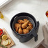 Black air fryer basket with cooked fried chicken drumsticks on kitchen worktop