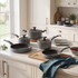 Grey non-stick saucepan and frying pan set on kitchen counter, lids included, shown in daylight