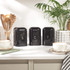 Set of three black kitchen storage canisters labelled S, C, T on countertop