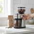 Electric coffee grinder in stainless steel with beans and ground coffee, in kitchen setting