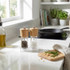 Pair of wooden salt and pepper grinders on kitchen counter with herbs and oil bottle