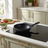 Black non-stick frying pan on induction hob in modern kitchen setting