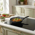 Black frying pan with stir fry vegetables on induction hob in modern kitchen setting