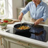 Non-stick black wok with stir-fry vegetables on induction hob, kitchen setting