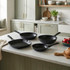 Set of four black non-stick frying and grill pans on kitchen worktop