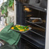 Baking tray of roasted vegetables and fish being placed in oven