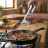 Electric pepper grinder seasoning steak and vegetables in frying pan on hob