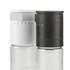Pair of adjustable white and black glass grinders for salt and pepper.
