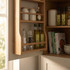 Kitchen cabinet shelf with olive oil bottles, spice jars and cookbooks.