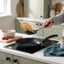 Non-stick frying pan in use, pancake being flipped with spatula in modern kitchen.