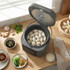 Electric multi-cooker with steamed dumplings, wooden spoon and sides on kitchen counter
