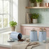Set of three blue kitchen storage canisters with lettered lids on a worktop