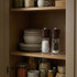 Set of salt and pepper grinders with dark wood tops on kitchen shelf