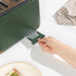 Hand removing crumb tray from green 4-slice toaster on kitchen counter