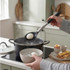 Egg spoon lifting boiled egg from saucepan into ice water bowl, kitchen setting
