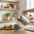 Chrome electric kettle pouring water into grey mug in modern kitchen