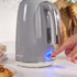 Grey electric kettle with chrome handle, being switched on