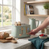 Pastel green four-slot toaster with bread, shown in a modern kitchen setting.