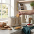 Four-slice cream toaster in kitchen with bread and hand inserting toast
