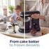 Black stand mixer with stainless steel bowl on kitchen worktop, set up for baking