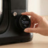 Hand adjusting dial on black kitchen appliance showing digital timer display