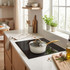 Cream saucepan with gold handle and lid on induction hob in modern kitchen