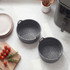 Set of two grey silicone air fryer liners with handles, shown on kitchen worktop.