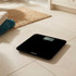 Black digital bathroom scale with LCD display on tiled floor
