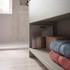 Silver digital bathroom scale on shelf beside folded towels and a wicker basket