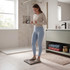Digital bathroom scale in use, shown on tiled floor with towels stored nearby